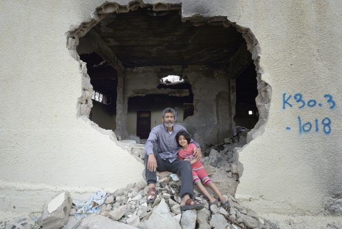 Fawzi Abu Jame'a, with his 7-year old daughter Raghad, sit in the ruins of what was once his parents' home Khan Yunis, Gaza. Houses in the area were destroyed by Israeli air strikes during the 2014 war between the state of Israel and the Hamas government of Gaza.