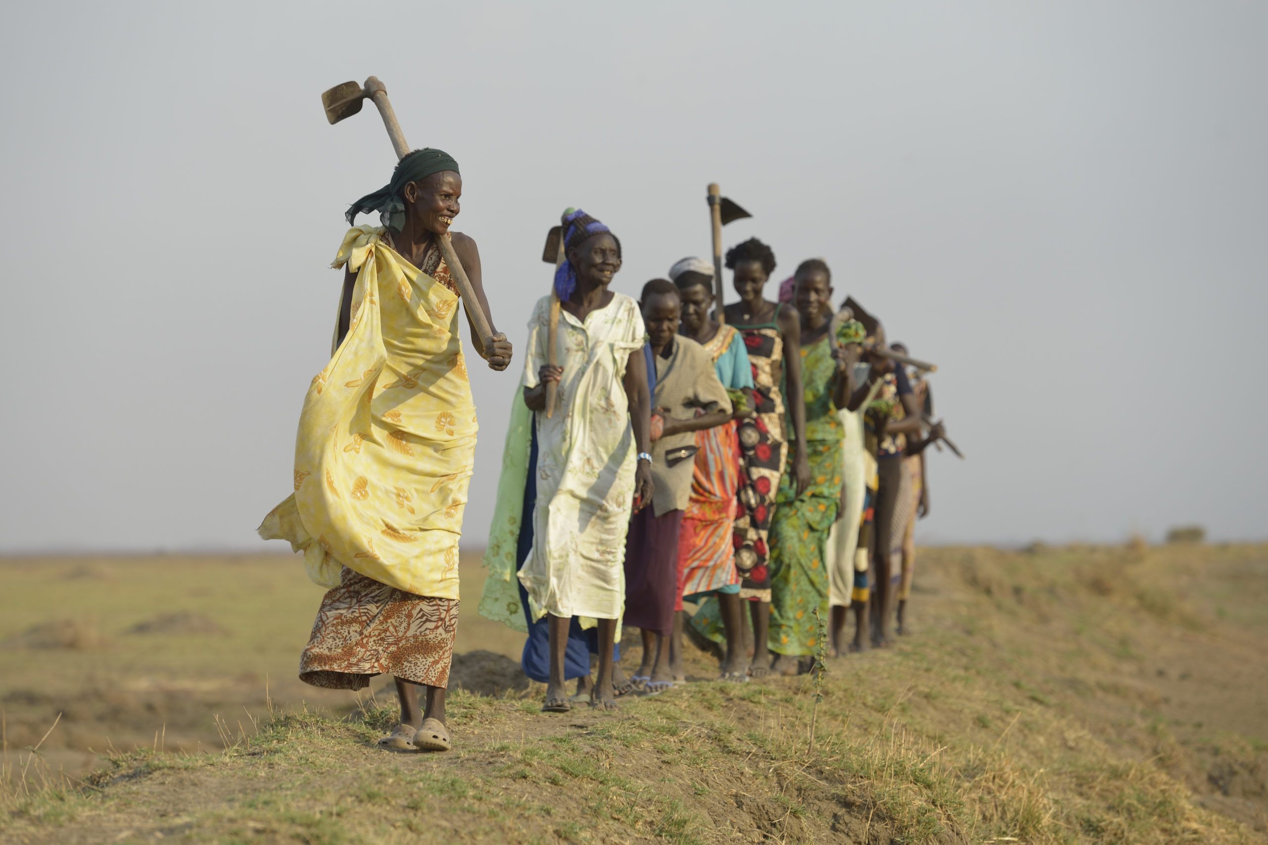 Women walking atop a dyke built to control flooding in South Sudan. Photo: Paul Jeffrey/ACT